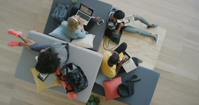 young group of multiracial college students study together using mobile technology working on project exam in modern recreational workspace top view