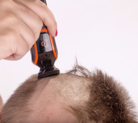 a woman's hand shaves her head with an electric thimble, an electric shaver