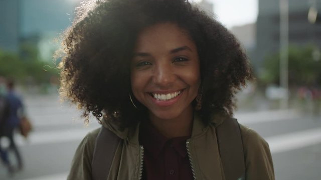 portrait of beautiful trendy african american woman smiling at camera looking confident running hand through hair enjoying urban city lifestyle
