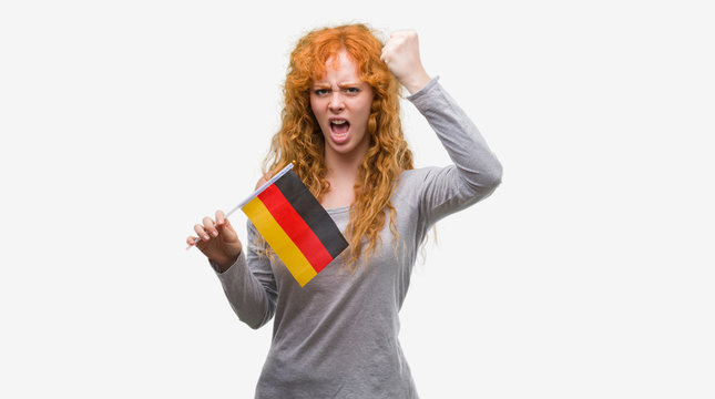 Young redhead woman holding flag of Germany annoyed and frustrated shouting with anger, crazy and yelling with raised hand, anger concept