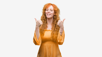 Young redhead woman success sign doing positive gesture with hand, thumbs up smiling and happy. Looking at the camera with cheerful expression, winner gesture.