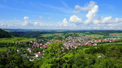 Blick von oben auf Dorf Gültlingen zwischen Wald und Wiesen und dramatischen weißen Wolken