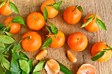 A lot of fresh Mandarins with green leaf on wooden background.