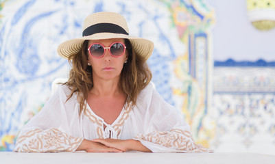 Middle age brunette woman sitting at the table with colorful background with a confident expression...