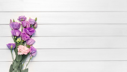 Beautiful purple eustoma flowers on white wooden background. Copy space, top view,