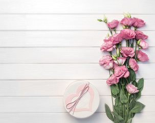 Beautiful pink eustoma flowers and handmade gift box on white wooden background. Copy space, top view,