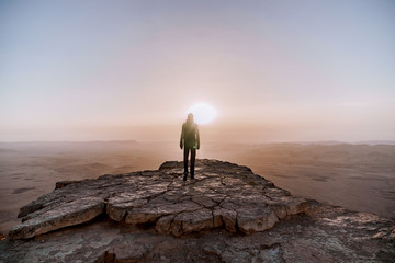Alone man in israel negev desert admires the view of sunrise. Young male person stands on the edge...