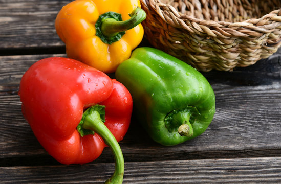 Mixed and colorful of bell pepper with basket on wooden floor.