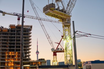 Toronto construction site with cranes and CN Tower at sunrise