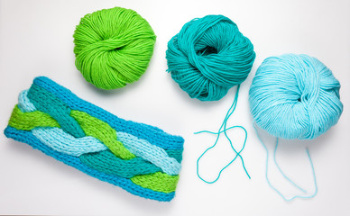 top view of colored yarn balls and knitting needles on white