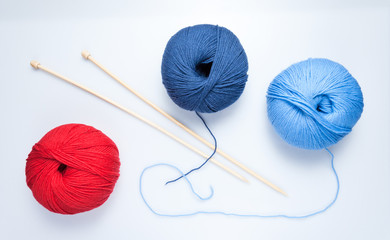 top view of colored yarn balls and knitting needles on white
