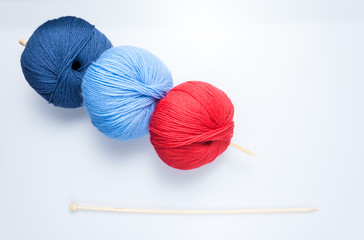 top view of colored yarn balls and knitting needles on white