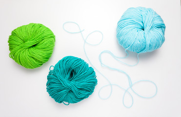 top view of colored yarn balls and knitting needles on white