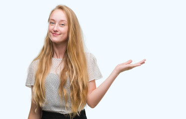 Blonde teenager woman wearing moles shirt smiling cheerful presenting and pointing with palm of...