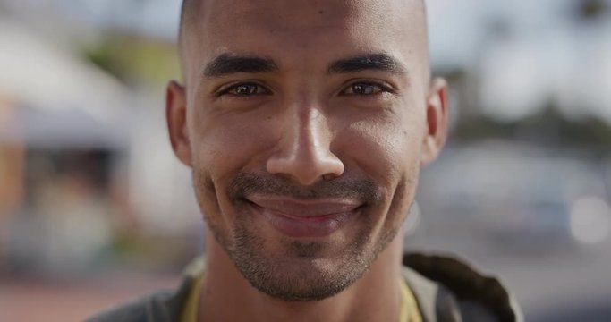close up portrait of handsome hispanic man smiling cheerful looking at camera happy enjoying warm summer on urban beachfront street