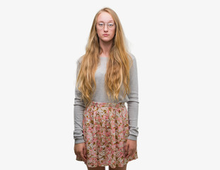 Blonde teenager woman wearing flowers skirt with serious expression on face. Simple and natural looking at the camera.