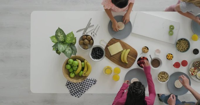 group of young multi ethnic girls making healthy homemade snacks together decorating using nutritious ingredients vibrant food in kitchen top view