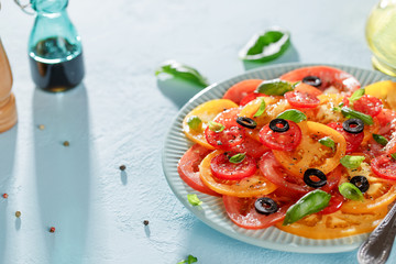 Homemade vegetarian tomato carpaccio salad in blue plate on blue background.