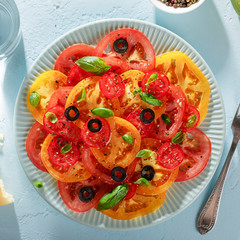 Blue plate with homemade vegetarian tomato carpaccio on blue background.