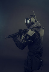 Cosplay futuristic solder with gun. Dark background.