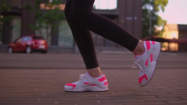 close up details legs sport outdoor. unrecognizable woman running down the street. feet shod in sneakers bright colors white and pink