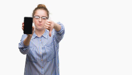 Young blonde woman using smartphone with angry face, negative sign showing dislike with thumbs...