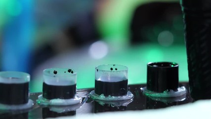 Tattoo artist dipping the machine needle into disposable ink cup. Woman working in black latex sterile gloves in tattoo saloon. Slow motion. 4k