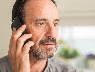 Middle age man using smartphone with a confident expression on smart face thinking serious