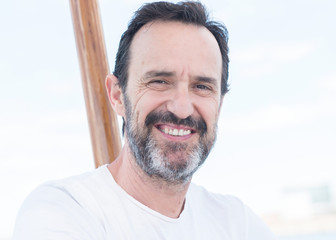 Fototapeta premium Handsome senior man traveling on sailboat and smiling happy and confident