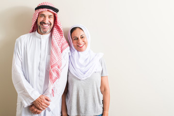 Middle age arabic couple, woman and man with a happy face standing and smiling with a confident smile showing teeth