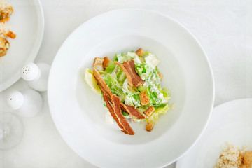 cesar salad topping with bacon on white plate