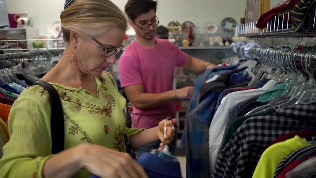 Mother pulls out a jumper for her son to look at while shopping for clothes.