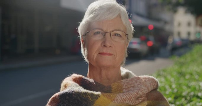portrait of beautiful elderly woman looking calm pensive at camera wearing scarf middle aged caucasian female retirement age in urban city background