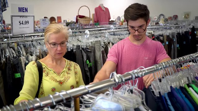 Mother and teen son shop for second hand clothing at a store.