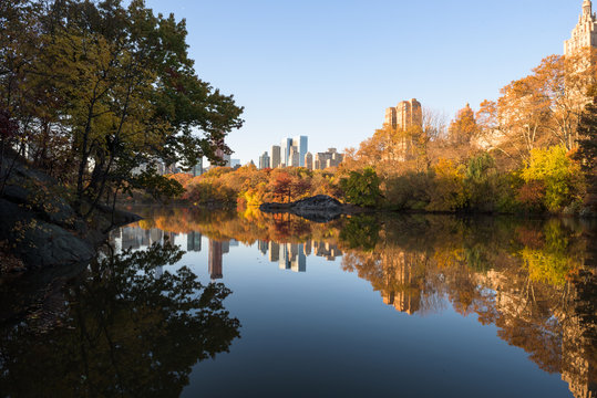 Skyline of Manhattan reflected in a pond in central park at sunrise, New York, United States of America