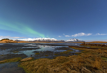 Winter lake near mountain in Hofn, Iceland. Northern lights and blue sky background.