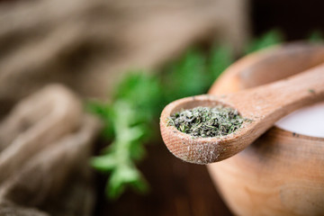 Dried Oregano in a Wooden Teaspoon Ready to Add to Bowl of Salt to make Herb Salt; Fresh sprig of oregano on wooden table