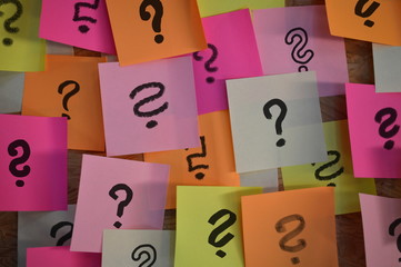 Handwritten different question marks on red, pink, white, yellow and orange sticky notes 