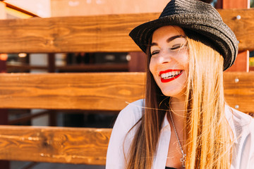 The girl closed her eyes with joy and smiled sincerely against the background of a wooden fence