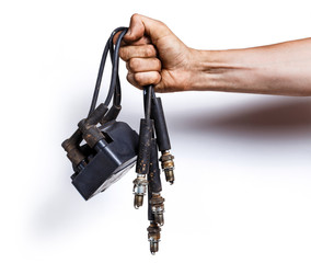 Auto mechanic with old high-voltage wires, spark plugs and ignition coil in hands. Isolated on...
