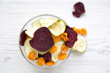 Top view, full bowl of veggie chips on white wooden table. From above, overhead, flat lay. Closeup.