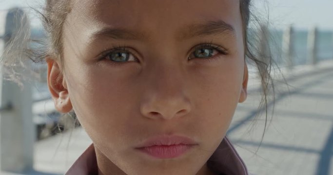 close up portrait young little mixed race girl looking serious contemplative kid on sunny seaside beach slow motion