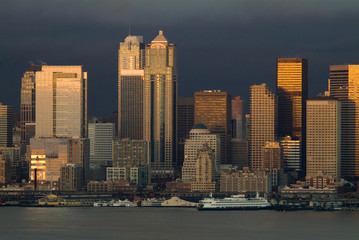 Obraz premium Dramatic Seattle, Washington Sunset Over Elliott Bay. Just after a rain squall the setting sun emerges to light up the skyscrapers along the Seattle waterfront.