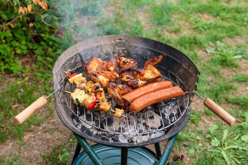 Grilling sausages, chicken wings and shashlicks on barbecue grill.