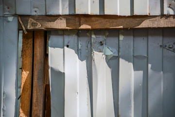 Damaged fence of boards and corrugated metal