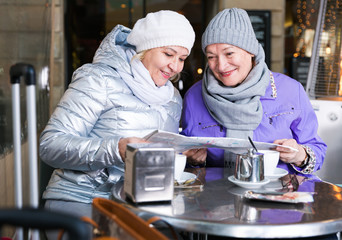 Fototapeta na wymiar Senior females reading city map in outdoors cafe
