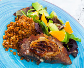 Delicious fried pork with lentils, avocado and orange at plate