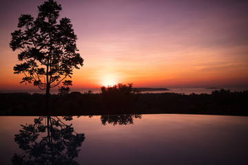 Fototapeta na wymiar Infinity pool of tropical resort at sunset