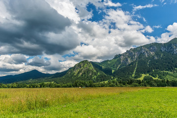 Fototapeta premium Idyllic landscape in the Alps with green meadows and clouds