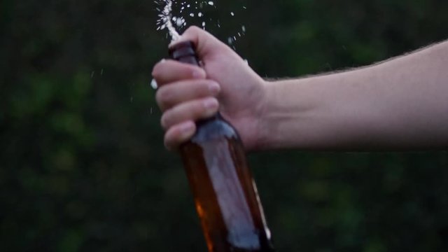 SLOW MOTION footage shaking a beer bottle with thumb over the hole and associated frothing